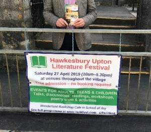 photo of Hugh Arthur holding his book by the Festival sign